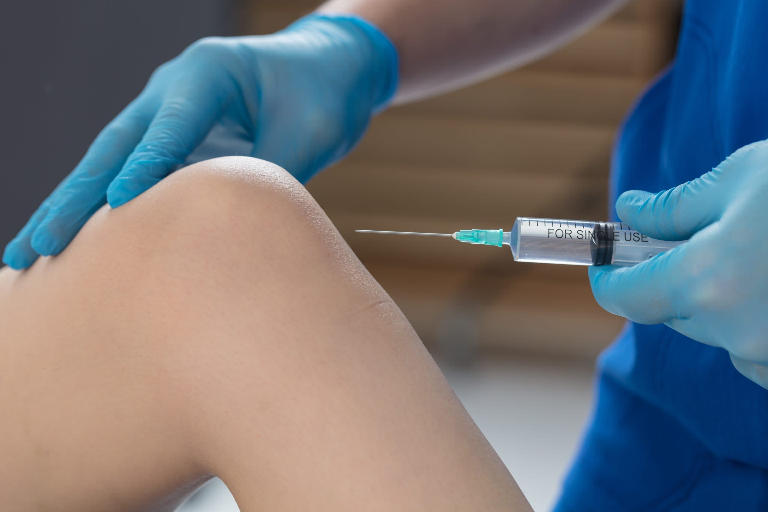 Close-up of knee injection with blue gloves